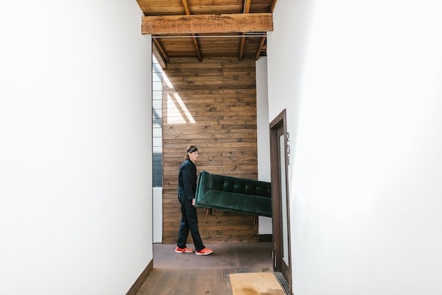 Man holding a big green sofa